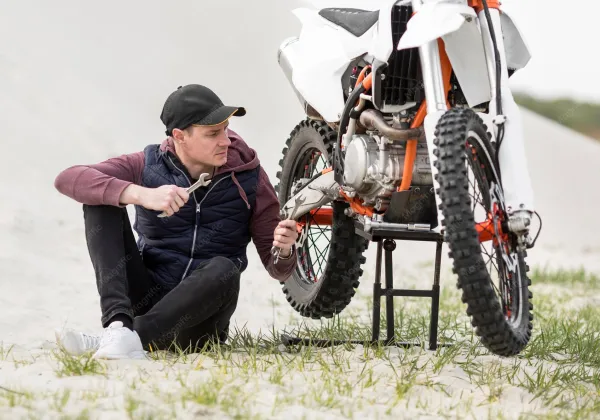 Mecânico conferindo moto de trilha ao ar livre