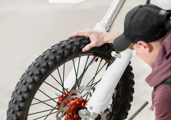 Mecânico conferindo a roda dianteira da moto de trilha